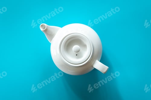 Preview: White teapot with tea on a blue background, flat lay.