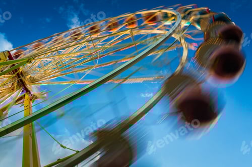 Preview: Blurry ferris wheel in motion on blue sky background