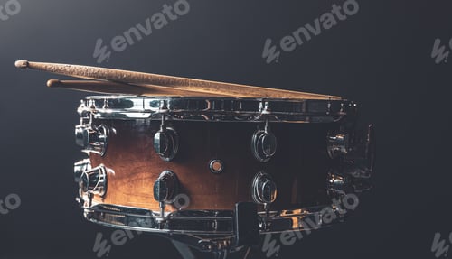 Preview: Close-up snare drum and drum sticks on a dark background.