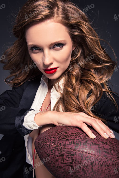 Preview: portrait of attractive woman holding american football ball isolated on gray