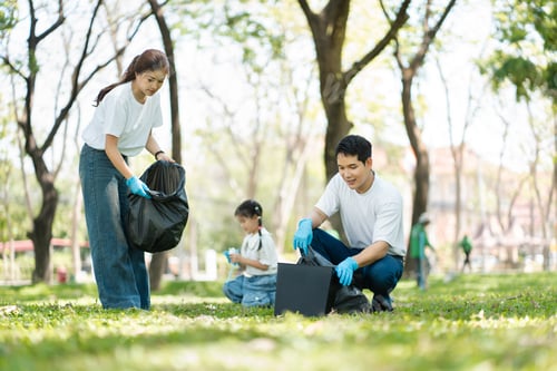 Preview: Happy Asian family collecting plastic bottles at the park.