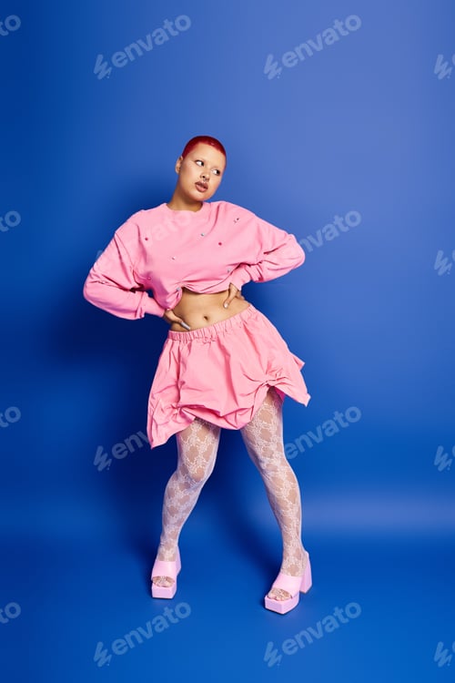 Preview: A bold young woman with pink hair showcases her unique style in a vibrant studio setting