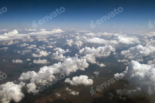 Preview: Aerial view from airplane window of white puffy clouds on bright sunny day.