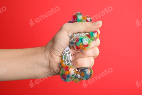 Preview: Woman squeezing colorful slime on red background, closeup. Antistress toy