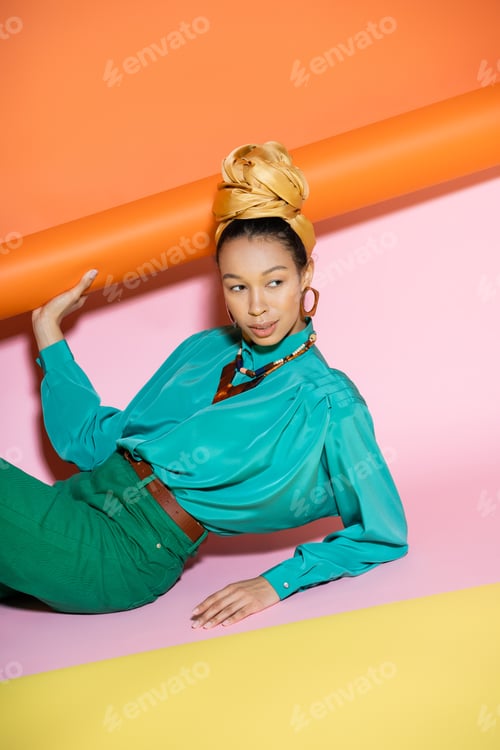 Preview: Trendy african american model in golden headscarf posing with colorful background