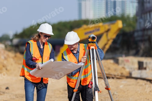 Preview: Two construction surveyors in safety gear work at a job site