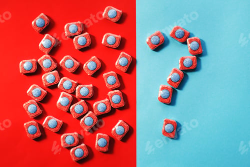 Preview: capsules for kitchen dishwashers and a question mark on a blue and red background. flat lay.