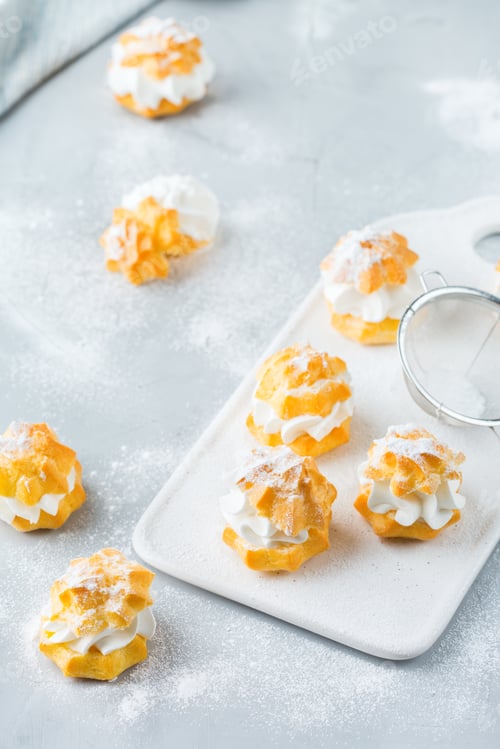 Preview: Delicious sweet profiteroles with cream on a modern kitchen table