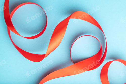 Preview: Red ribbon on a blue pastel background. Top view, copy space.