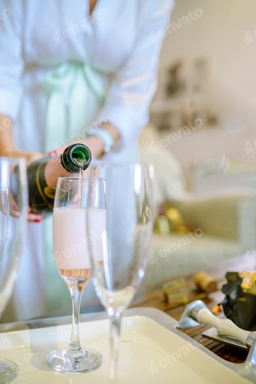 Preview: Faceless woman pouring champagne into wineglass