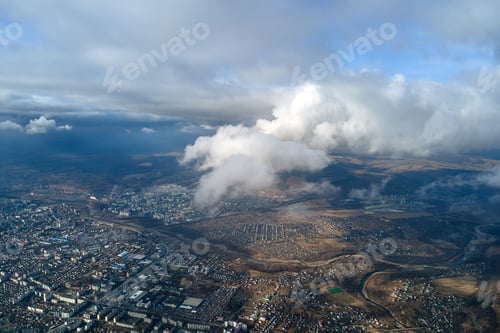 Preview: Aerial view from high altitude of distant city covered with puffy cumulus clouds