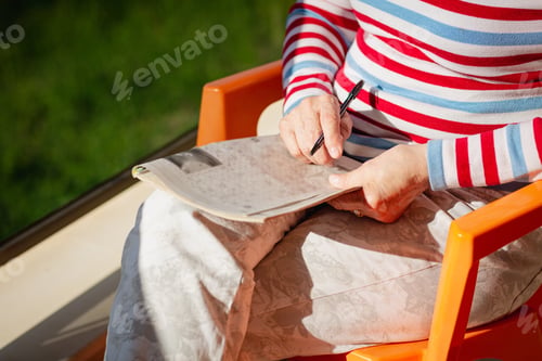 Preview: Elderly woman in glasses sitting on balcony near the sea