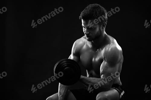 Preview: Monochrome shot of an athletic ripped young sportsman with dumbb