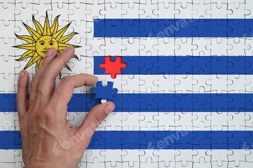 Preview: Uruguay flag is depicted on a puzzle, which the man's hand completes to fold.