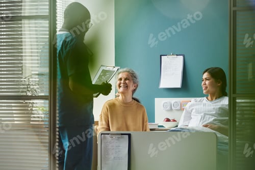Preview: Senior and Young Pregnant Women Smiling While Talking with Black Male Nurse