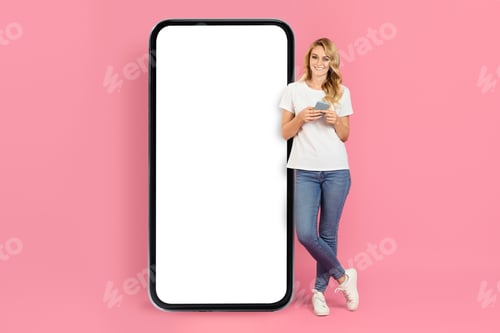 Preview: Woman beside a large smartphone with a blank screen on pink