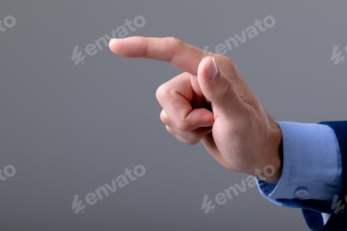 Preview: Midsection of caucasian businessman pointing with his finger, isolated on grey background