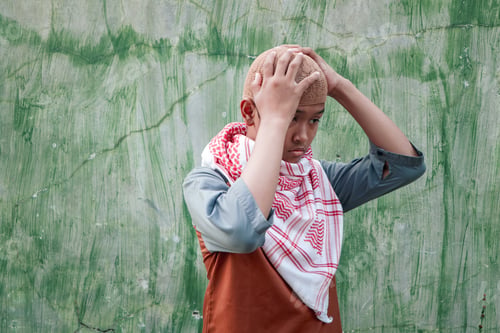 Preview: An Asian boy is wearing a cap and a turban.