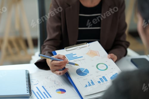 Preview: Business professional reviewing detailed financial reports and charts with a colleague, highlighting
