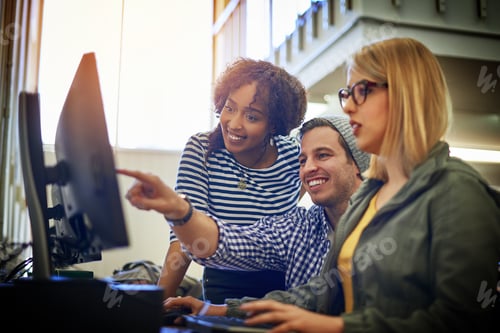 Preview: Shot of a group of university students working together on a computer in the library at campus