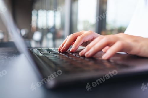 Preview: Closeup image of a woman working and typing on laptop computer keyboard on the table