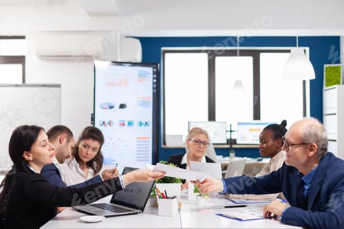 Preview: Young employee exchanging documents with senior executive