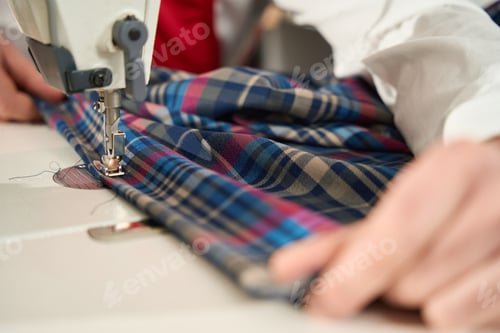 Preview: Professional tailor using overlocker in clothing workshop