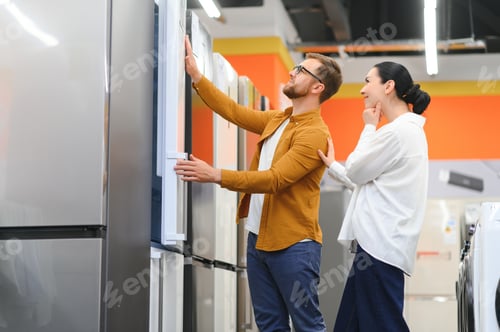 Preview: Young couple, satisfied customers choosing fridge in appliances store