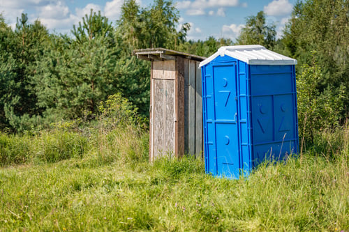 Preview: Edge of the forest stands an old wooden toilet and a new plastic toilet.