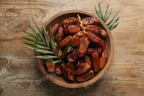 Preview: Bowl of sweet dried dates on wooden table, top view
