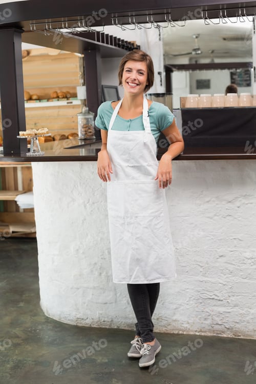 Preview: Pretty barista smiling at camera at the coffee shop