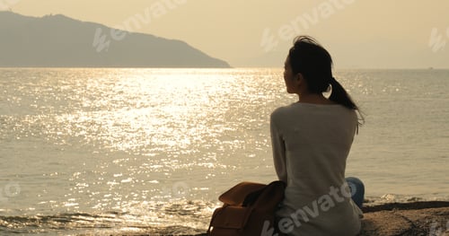 Preview: Woman looking at the sea under sunset