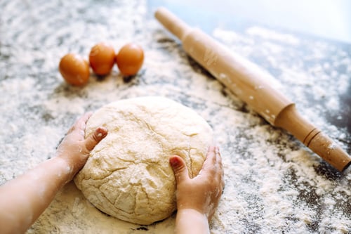 Preview: Children hands kneading dough on wooden table. Easter baking preparation. Cookies for Christmas.