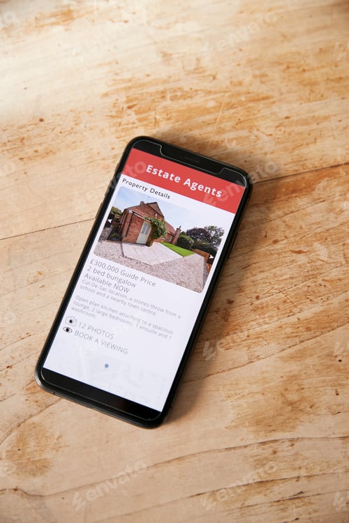 Preview: Close Up Of Mobile Phone With Realtors Property App Lying On Table