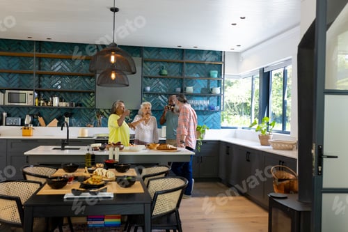 Preview: At home, Group of senior friends toasting with wine glasses in modern kitchen