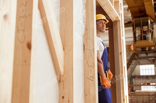 Preview: Male builder standing in doorway of wooden construction cabin
