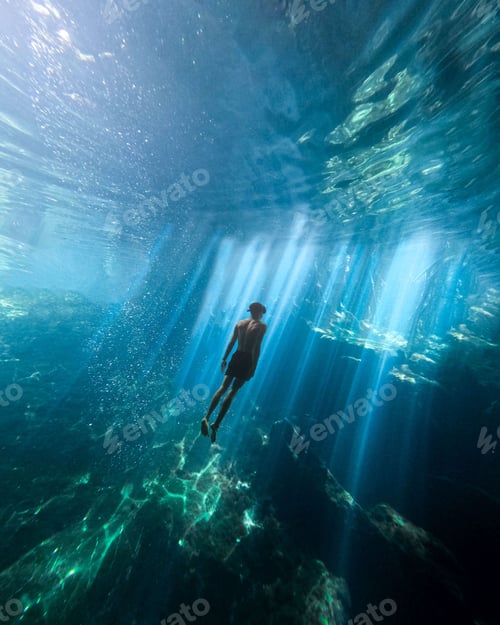 Preview: Vertical shot of a male swimming completely underwater