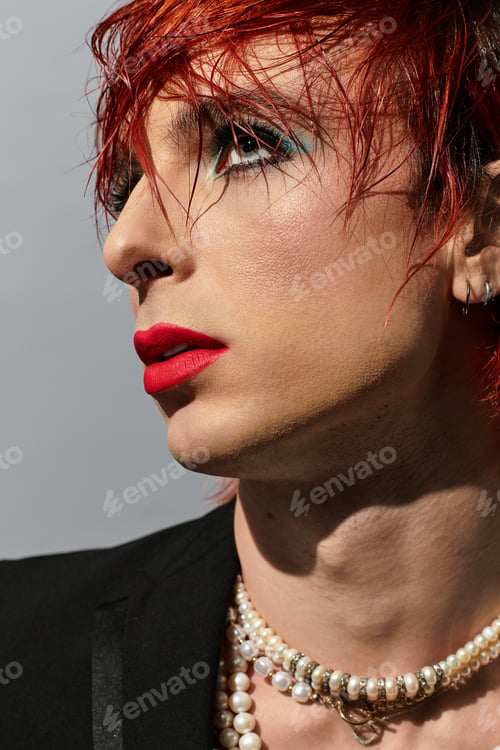 Preview: A young man with vibrant red hair and bold makeup showcases his individuality with flair.