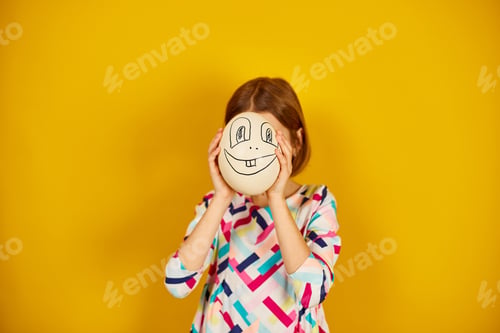 Preview: Playful teenager girl covering her face of Ostrich egg with funny face