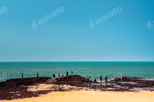 Visualização: Turistas na praia tropical e arenosa de Anjuna, na costa de Goa, com céu azul, Índia