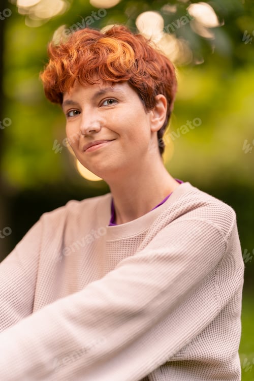 Preview: Positive androgynous woman with red hair in nature