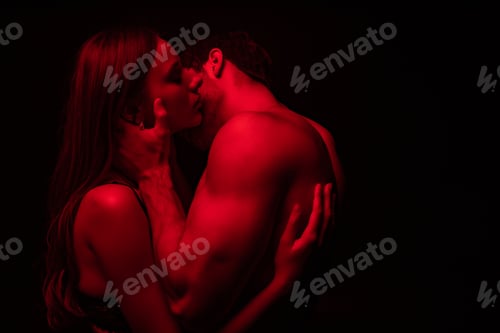 Preview: side view of passionate undressed sexy young couple kissing in red light isolated on black