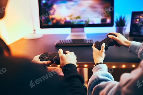 Preview: Friends playing video game at home. Gamers holding gamepads sitting at front of screen. Streamers