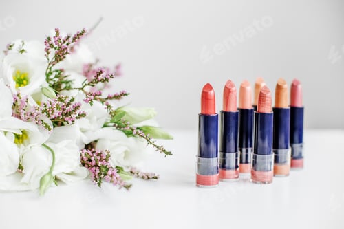 Preview: Set of colored lipsticks. Concept of cosmetics and care. Beautiful flowers. Copy space