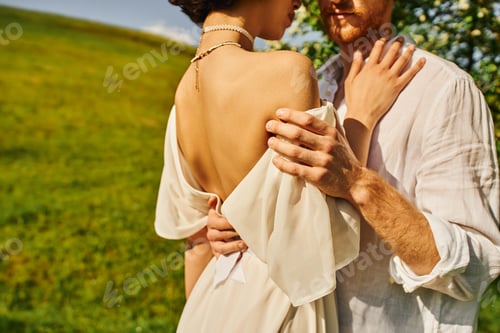 Preview: cropped view of sensual couple of newlyweds embracing each other in green garden, rural wedding