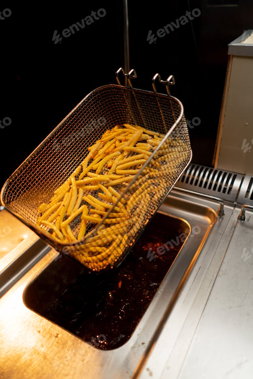 Preview: professional kitchen in hotel restaurant the chef takes out delicious french fries from the fryer