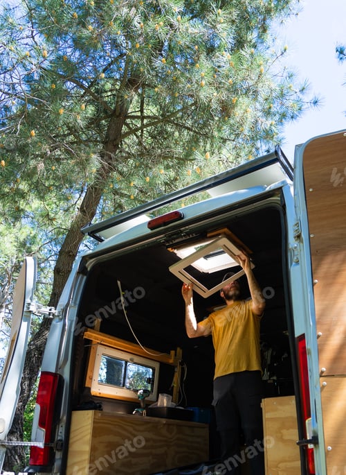Preview: Handyman installing camper van roof window in pine forest