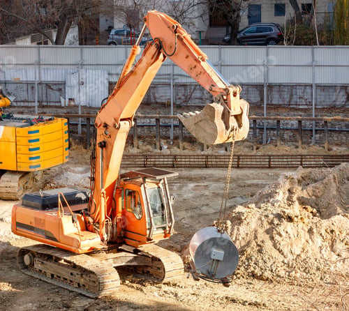 Preview: Heavy crawler excavator lifting a large mortar mixer on a construction site