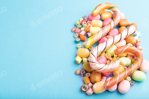 Preview: Various caramel candies on blue background. copy space, side view