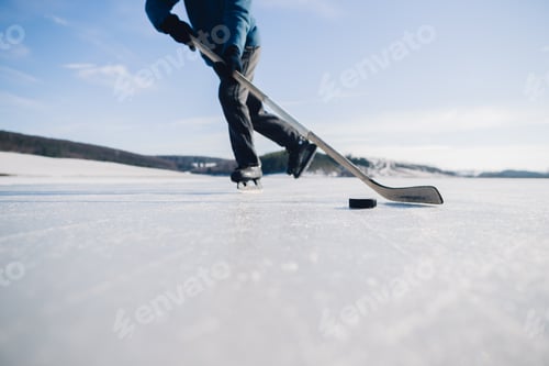 Preview: An elderly man practices stricking the puck with hockey stick on a frozen lake in winter.